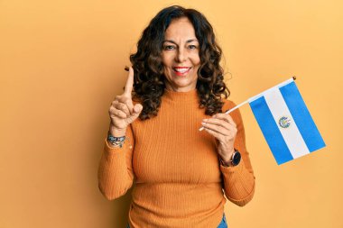 Orta yaşlı İspanyol kadın elinde bir fikir ya da soruyla gülümseyen bir El Salvador bayrağı tutuyordu. 