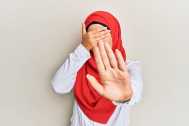 Geleneksel İslami başörtüsü takan genç, güzel İspanyol kız elleriyle gözlerini kapatıyor ve üzgün ve korku ifadeleriyle jest yapıyor. utangaç ve olumsuz kavram. 
