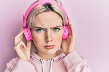 Genç sarışın kız müzik dinliyor kulaklık takıyor şüpheci ve gergin, sorun yüzünden surat asıyor. negatif kişi. 