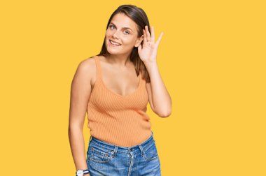 Gündelik kıyafetler giyen, el pençe divan gülümseyen, dedikoduları ve dedikoduları dinleyen genç beyaz bir kadın. Sağırlık kavramı. 