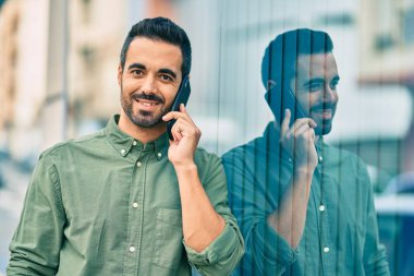 Genç İspanyol adam gülümsüyor. Şehirdeki akıllı telefondan konuşuyor..