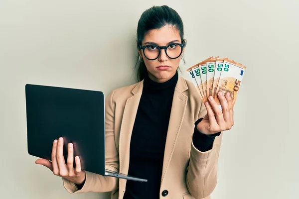 Mulher Hispânica Jovem Vestindo Estilo Negócios Segurando Laptop Euros Deprimido — Fotografia de Stock