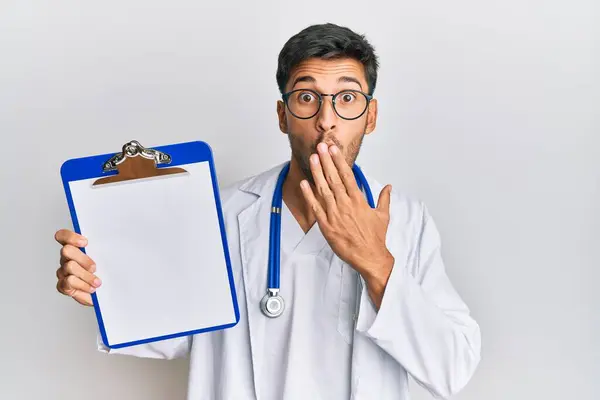 Joven Hombre Guapo Con Estetoscopio Médico Sosteniendo Portapapeles Cubriendo Boca — Foto de Stock