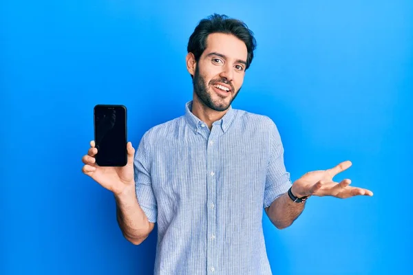 Молодий Іспаномовний Чоловік Тримає Смартфон Показуючи Екран Святкуючи Досягнення Щасливою — стокове фото