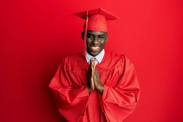 年轻的非洲裔美国人头戴毕业帽 头戴礼袍 手牵着手祈求宽恕 充满自信地微笑着 — 图库照片