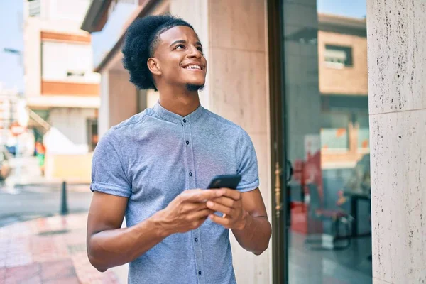 若いアフリカ系アメリカ人の男が市内のスマートフォンを使って笑顔で — ストック写真