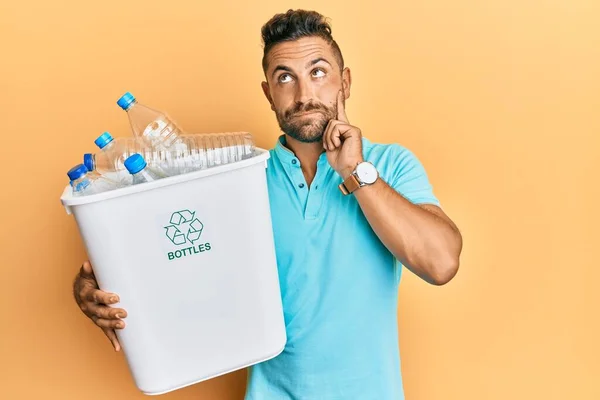 Przystojny Facet Brodą Trzymający Kosz Śmieci Plastikowymi Butelkami Poważnie Myśli — Zdjęcie stockowe