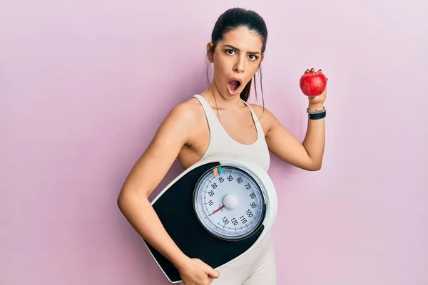 Młoda Latynoska Kobieta Nosząca Odzież Sportową Wagą Jabłkiem Szokującej Twarzy — Zdjęcie stockowe