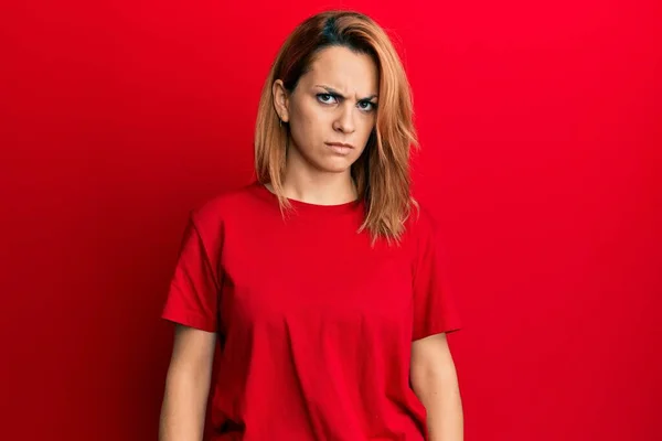 ヒスパニック系の若い女性が問題のために動揺を眉をひそめて 懐疑的で緊張したカジュアルな赤いTシャツを着ている 否定的な人 — ストック写真