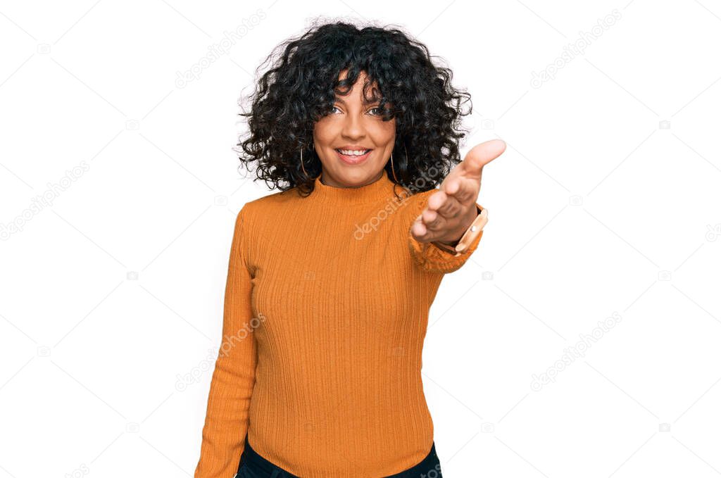 Young hispanic woman wearing casual clothes smiling friendly offering handshake as greeting and welcoming. successful business. 