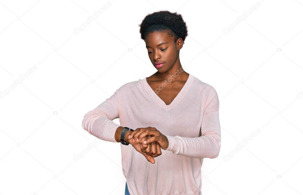 Young african american girl wearing casual clothes checking the time on wrist watch, relaxed and confident 