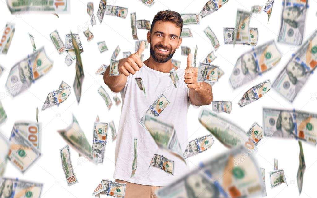 Young hispanic man wearing casual white tshirt approving doing positive gesture with hand, thumbs up smiling and happy for success. winner gesture.