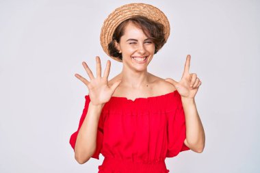 Genç İspanyol kadın yaz şapkası takıyor ve yedinci parmaklarını göstererek gülümsüyor. Kendinden emin ve mutlu.. 