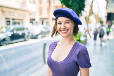 Genç, güzel bir kız, gülümsüyor. Fransız usulü. Şehrin caddesinde yürüyor.