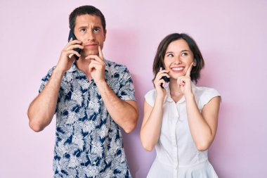 Akıllı telefonda konuşan güzel bir çift. Ciddi bir yüz ifadesi. Elleri çenede soru sormayı düşünüyorlar. 