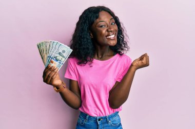 Dolarları tutan güzel Afrikalı genç bir kadın gururla bağırıyor, zaferi ve başarıyı kutluyor. 