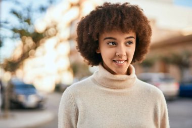 Genç İspanyol kız gülümseyerek şehirde mutlu mesut dikiliyor..