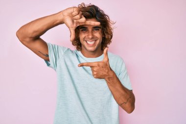 Gündelik kıyafetler giyen, gülümseyen, elleri ve parmakları gülen yüzlü, çerçeveli bir İspanyol. yaratıcılık ve fotoğrafçılık kavramı. 