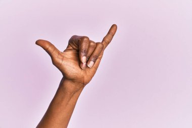 Siyah orta yaşlı kadının eli ve kolu pembe izole edilmiş arka planda Hawaii Shaka jesti, telefon ve iletişim sembolü. 