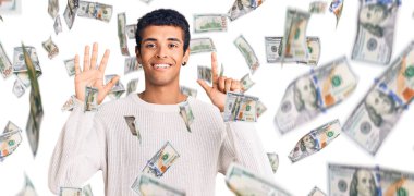 Genç Afrikalı Amerikalı günlük kıyafetler giymiş yedi numaralı parmaklarıyla işaret ederken kendinden emin ve mutlu bir şekilde gülümsüyor..