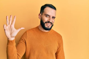 Sakallı, sıradan bir kazak giyen, dört numaralı parmaklarıyla işaret eden, kendinden emin ve mutlu bir genç adam.. 