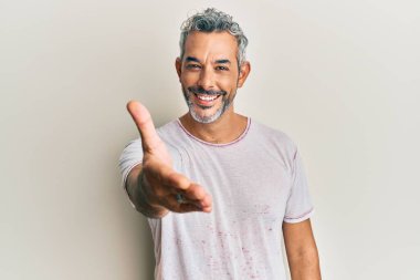 Orta yaşlı, gri saçlı, günlük kıyafetler giyen, gülümseyen, dostça el sıkışan bir adam. başarılı iş. 