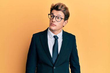 Yakışıklı, beyaz takım elbiseli ve kravatlı bir adam. Gülümsüyor, yan tarafa bakıyor ve düşünüyor.. 