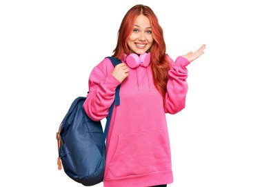 Öğrenci çantası ve kitapları tutan genç kızıl saçlı kadın zaferi mutlu bir gülümsemeyle ve ellerini kaldırarak kazanan ifadeyle kutluyor. 