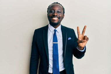 Yakışıklı, takım elbiseli ve kravatlı genç bir adam kameraya gülümseyen ve zafer işareti yapan. İki numara.. 