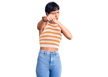 Kısa saçlı esmer bir kadın. Günlük kıyafetler giyiyor. Yumruk yumruğa dövüşüyor. 