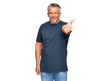 Orta yaşlı, gri saçlı, günlük kıyafetler giyen, gülümseyen, dostça el sıkışan bir adam. başarılı iş. 