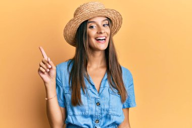 Bir fikir veya soruyla gülümseyen yaz şapkası takan genç İspanyol kadın mutlu bir yüzle işaret ediyor, bir numara. 