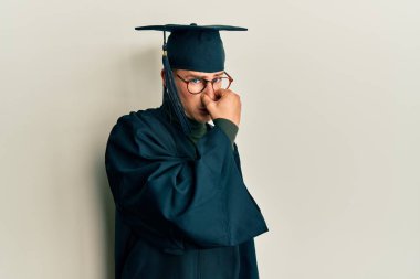 Mezuniyet şapkası ve tören cübbesi giyen genç beyaz bir adam pis ve iğrenç bir koku alıyor. Dayanılmaz bir koku. Parmakları burnunda nefesini tutuyor. Kötü kokuyor. 