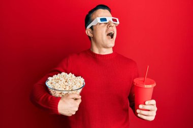Yakışıklı genç adam patlamış mısır yiyip gazoz içiyor 3D gözlükler takıyor kızgın ve kızgın çığlıklar atıyor sinirli ve öfkeli, öfkeyle bağırıyor.. 