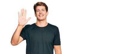 Yakışıklı, beyaz bir adam. Günlük kıyafetler giymiş. Beş numarayı gösteriyor ve gülümsüyor.. 