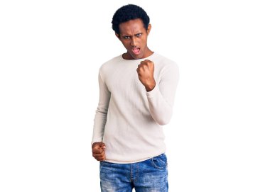 Öfkeyle bağırırken kızgın ve öfkeli bir şekilde yumruk kaldıran, sıradan bir kazak giyen Afrikalı yakışıklı adam. öfke ve agresif konsept. 