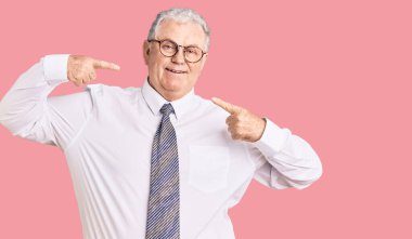 İş kıyafetleri giyen, neşeli gülümseyen, parmaklarıyla ve ağzıyla işaret eden yaşlı gri saçlı adam. diş sağlığı kavramı. 