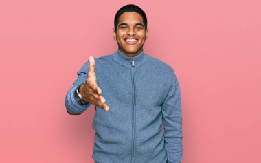 Hoş geldin ve hoş geldin demek için gülümseyen, sıradan bir eşofman giyen genç, yakışıklı İspanyol adam. başarılı iş. 