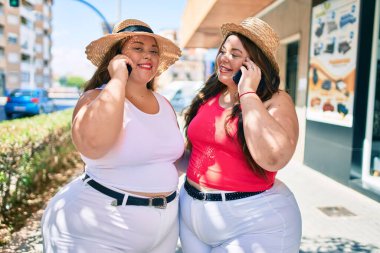 İki tane kilolu abla ikiz kız kardeş güneşli bir günde telefonda konuşan kadınlar.