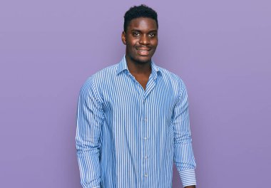 Yakışıklı iş adamı sıradan çizgili tişört giyiyor. Pozitif ve mutlu görünüyor. Kendine güvenen bir gülümsemeyle dişlerini gösteriyor. 