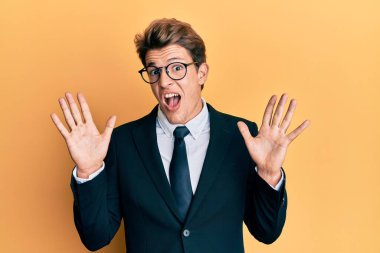 Yakışıklı, beyaz takım elbiseli, kravatlı çılgın kutlamalar yapan ve kolları açık, gözleri açık heyecanlı bir şekilde başarıyı kutlayan bir adam. Kazanan konsept 