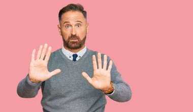 İş kıyafetleri giymiş yakışıklı orta yaşlı bir adam. Avuçlarını hareket ettiriyor. Korkmuş ve iğrenç bir ifadeyle reddediyor. Dur ve yasakla. 