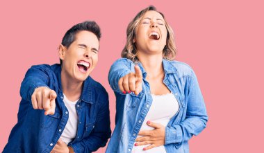 Gündelik giysiler içinde sana gülen, eli vücudunun üzerinde kamerayı işaret eden, utanç ifadesi takınan iki kadın. 