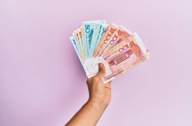 Hispanik el ele tutuşma Çin Yuan banknotları kapalı pembe arka plan.