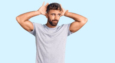 Gündelik kıyafetler giyen, tavşan kulağı yapan, avuçlarıyla alaycı ve şüpheci görünen genç İspanyol bir adam. Paskalya tavşanı konsepti. 