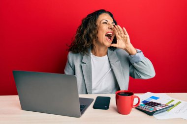 Ofiste çalışan orta yaşlı güzel bir kadın bir fincan kahve içip bağırıyor ve ağızdan ağıza bağırıyor. iletişim konsepti. 