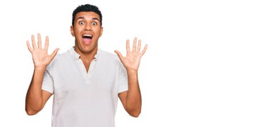 Genç Arap adam gündelik giysiler giyip çılgınlığı kutluyor ve başarıya hayret ediyor kolları açık ve gözleri açık heyecanla haykırıyor. Kazanan konsept 