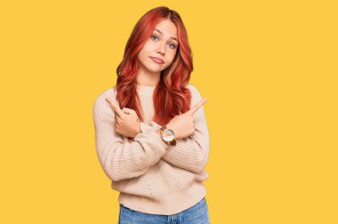 Kış süveteri giyen genç, kızıl saçlı kadın parmaklarıyla her iki tarafı işaret ediyor, farklı yönlere bakıyor. 