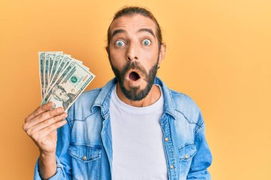 Uzun saçlı ve sakallı çekici bir adam elinde 20 dolarlık banknot tutuyor. Şaşırmış ve şaşırmış bir şekilde ağzı açık, inançsız bir yüz. 