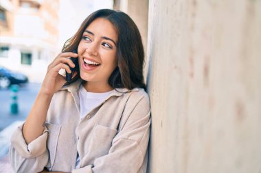 Genç İspanyol kadın gülümsüyor. Şehirdeki akıllı telefondan konuşuyor..